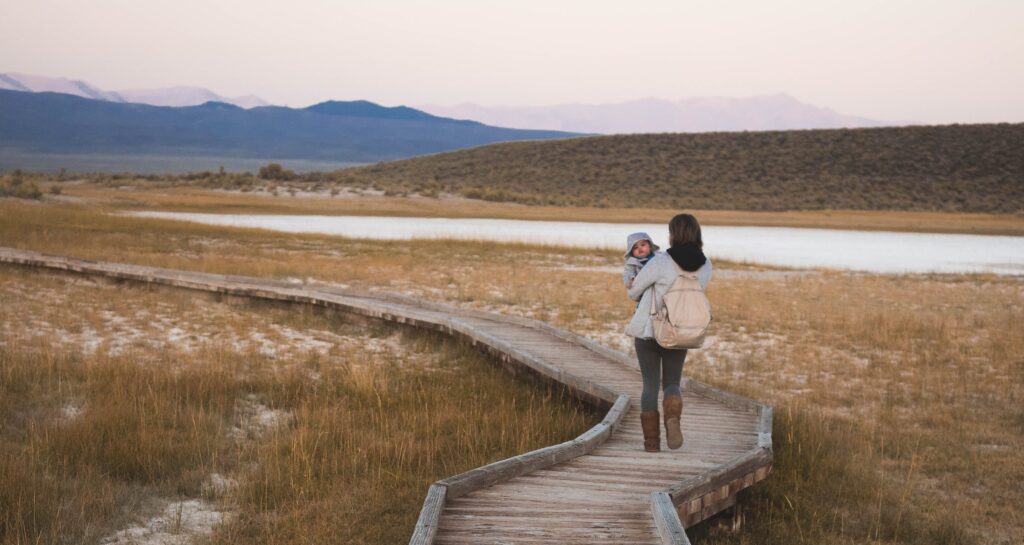 woman walking on wooden path with baby